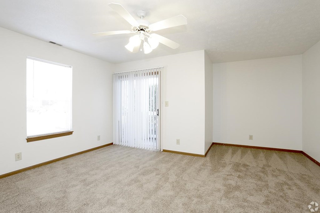 A room with a ceiling fan and carpeted floor.