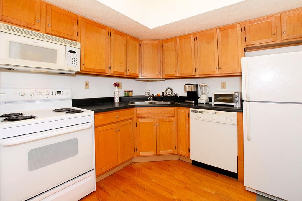 A kitchen with wooden cabinets and white appliances.