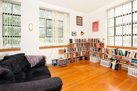 A living room with a black couch and a bookshelf filled with books.
