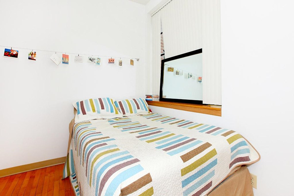 A bed with a striped comforter is in a room with a mirror and pictures on the wall.