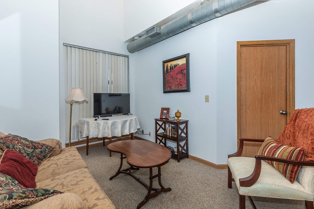 A living room with a couch, a coffee table, a television, and a painting on the wall.