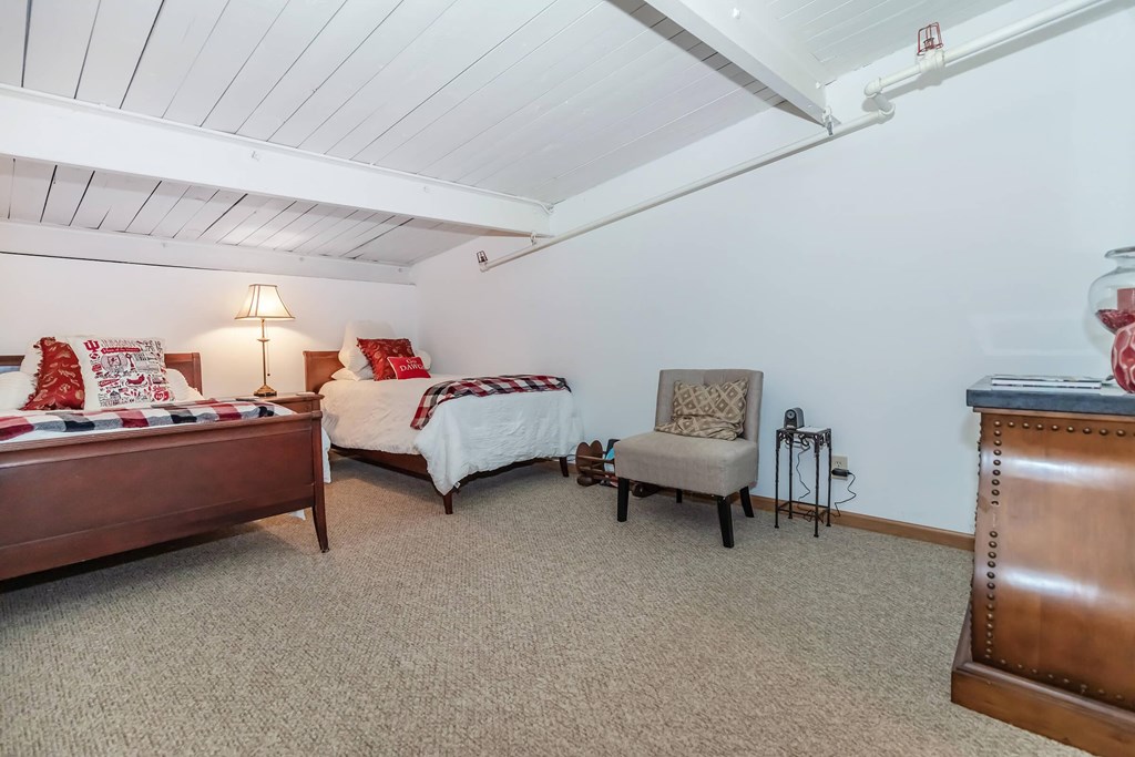 A bedroom with two beds and a chair.