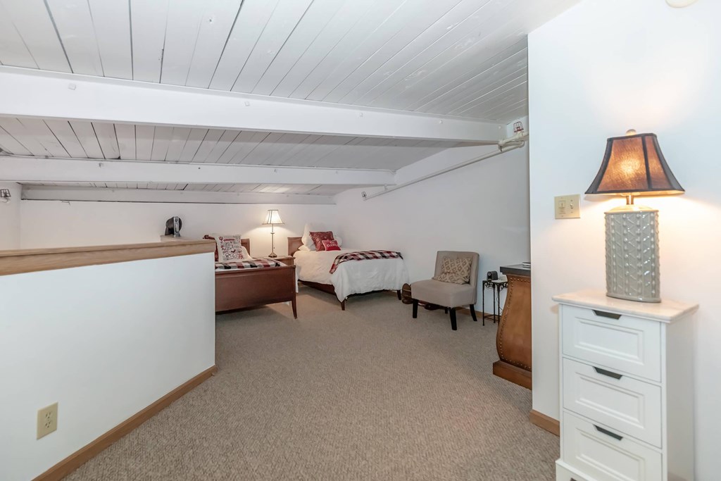 A bedroom with a bed, chair, and lamp.