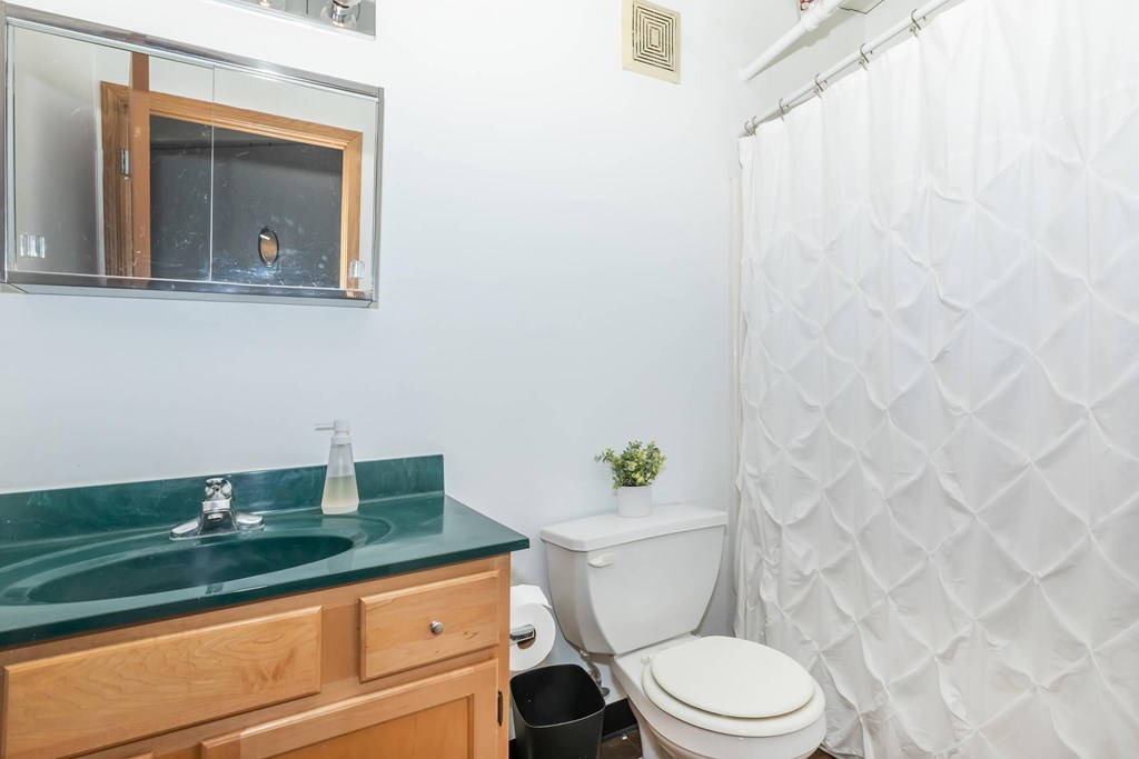 A bathroom with a green counter top and a white toilet.