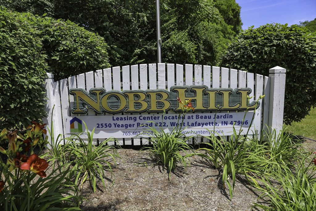 A sign for Nobb Hill Leasing Center is displayed in front of a white fence.
