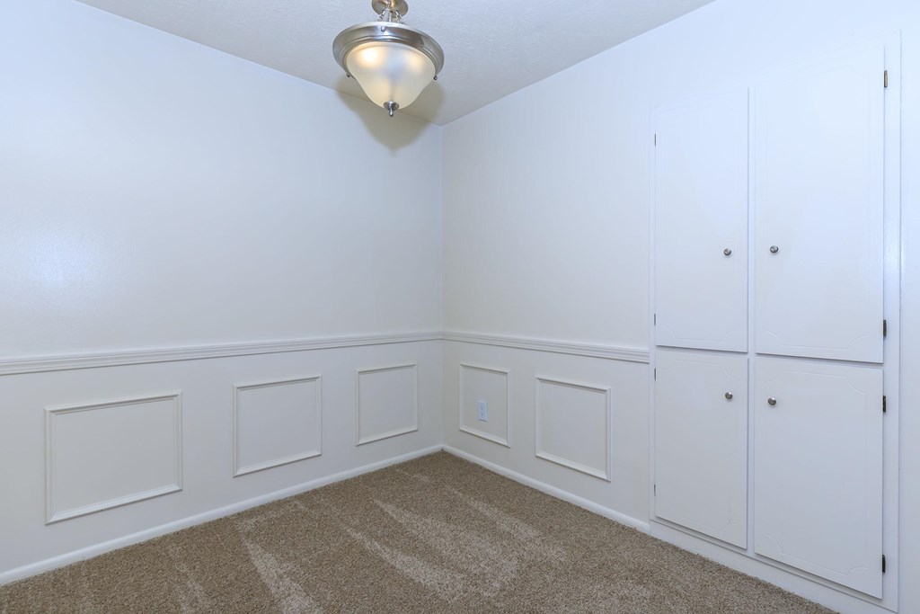 A white room with a carpeted floor and a light fixture on the ceiling.