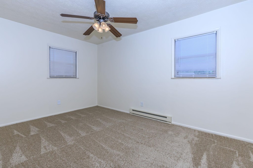A room with a ceiling fan and carpeted floor.