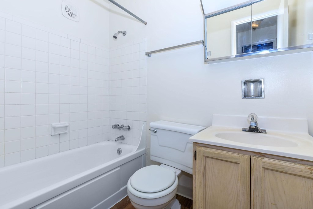 A white tiled bathroom with a white toilet, white sink, and white bathtub.