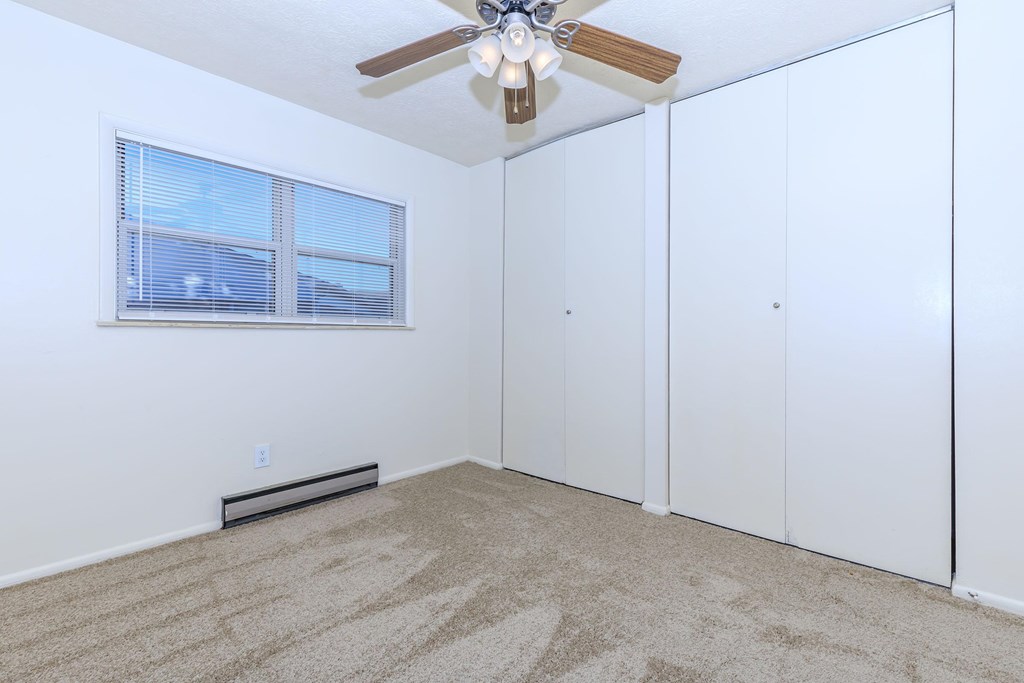 A room with a ceiling fan and carpeted floor.