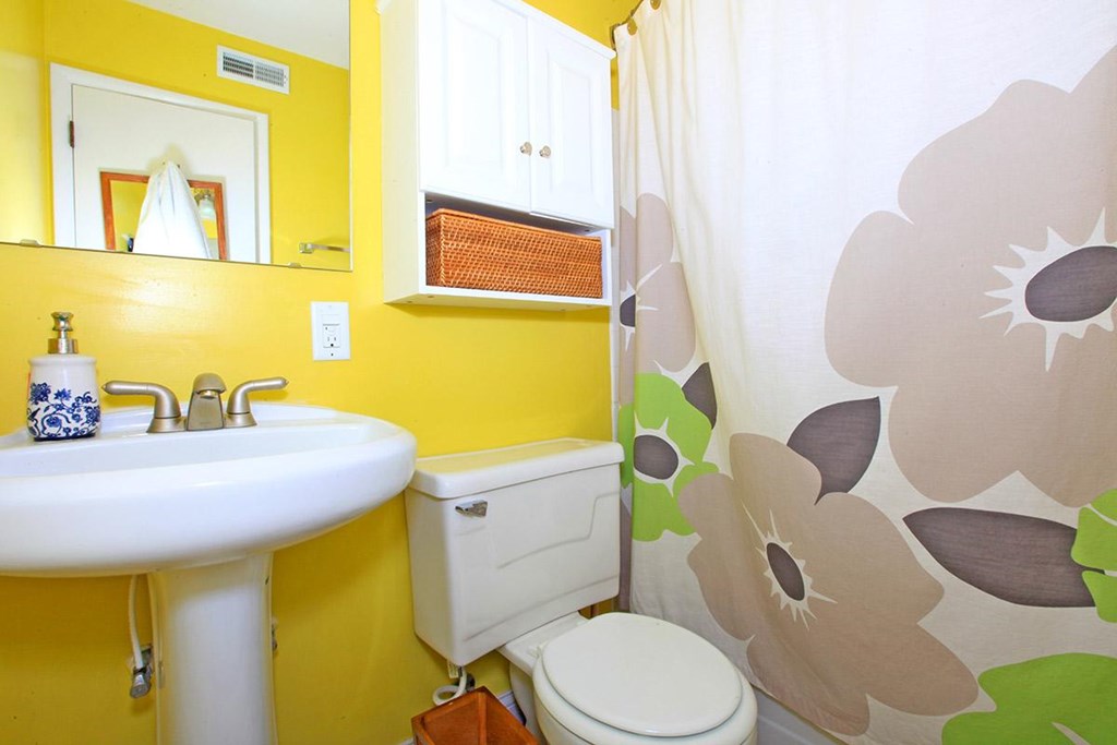 A bathroom with yellow walls and a white sink.