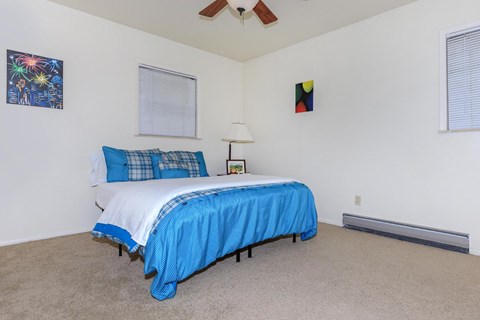 A bedroom with a bed covered in a blue bedspread.