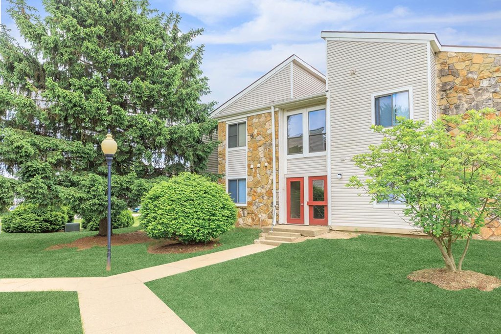 A building with a red door and a tree in front of it.