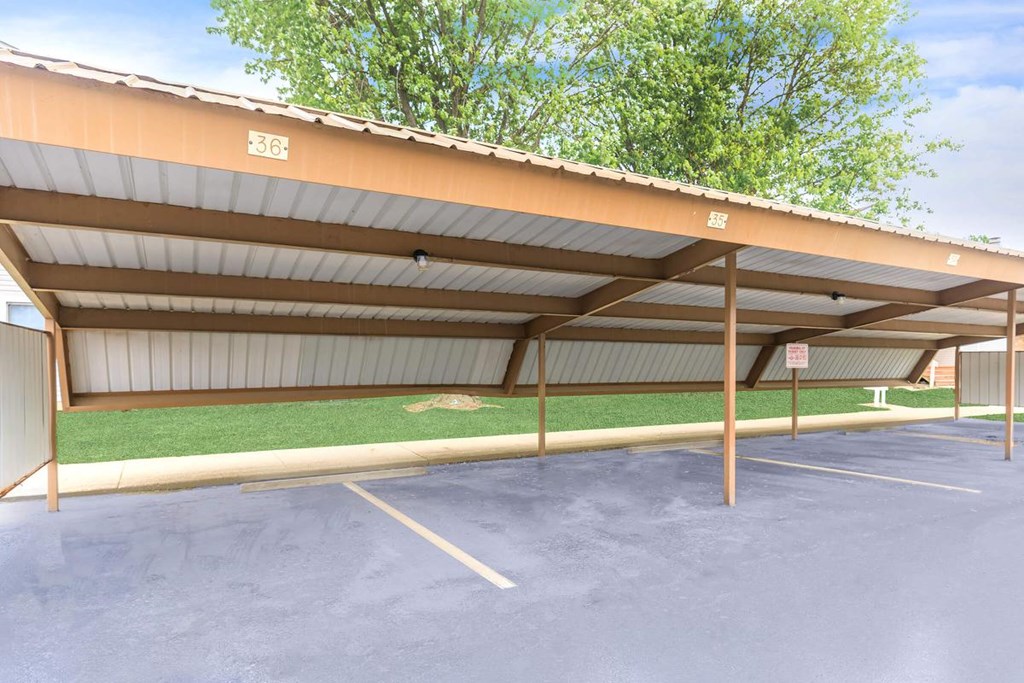 A parking lot with a building and a green lawn.