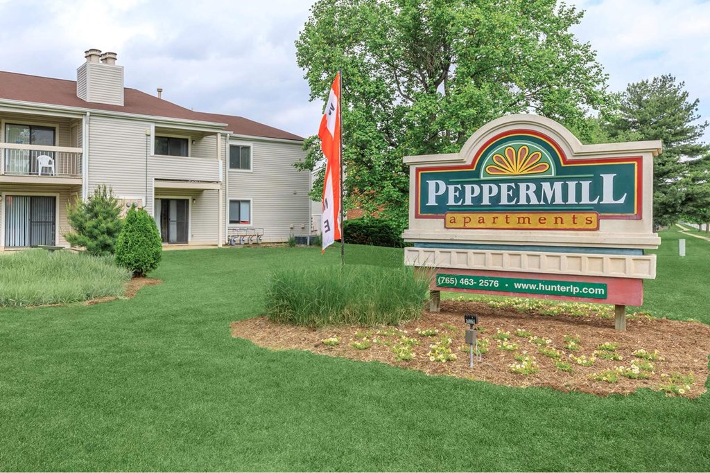 A sign for Peppermill Apartments is in front of a building.