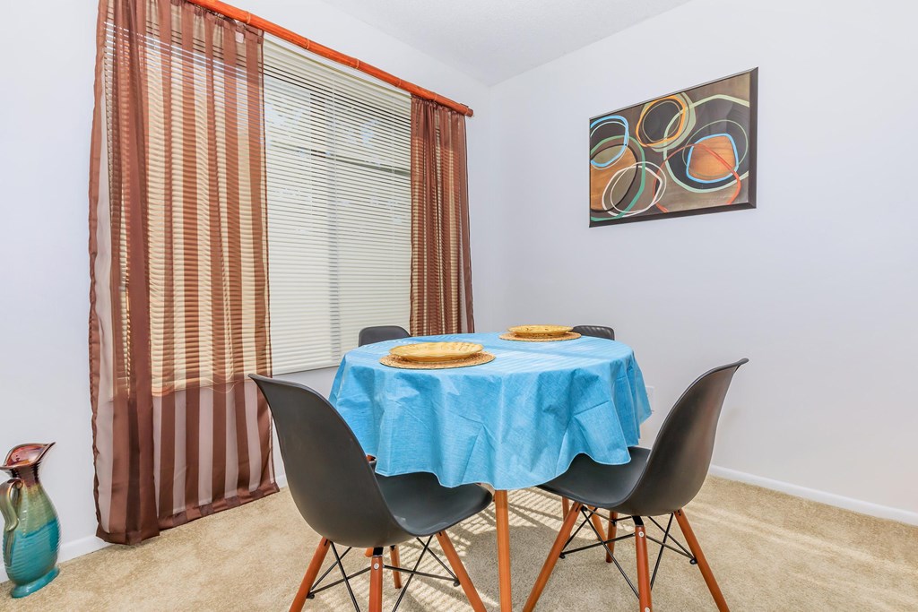 A dining table with a blue tablecloth and two chairs.