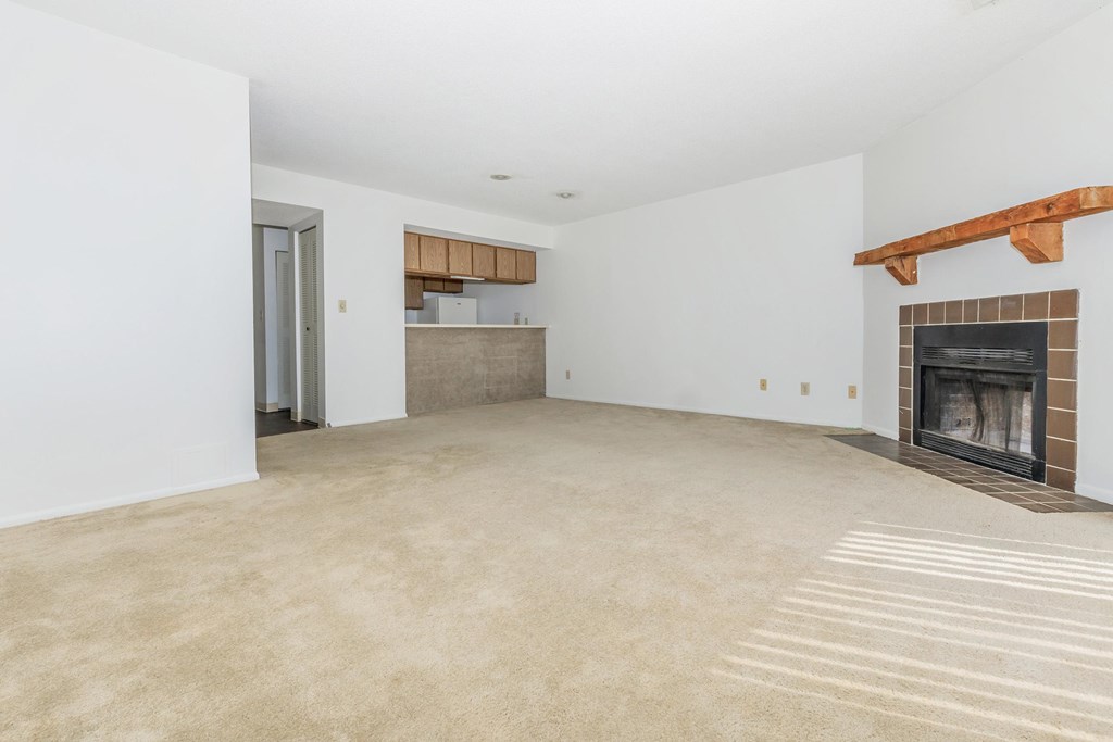 A large, empty room with a fireplace and a doorway leading to another room.