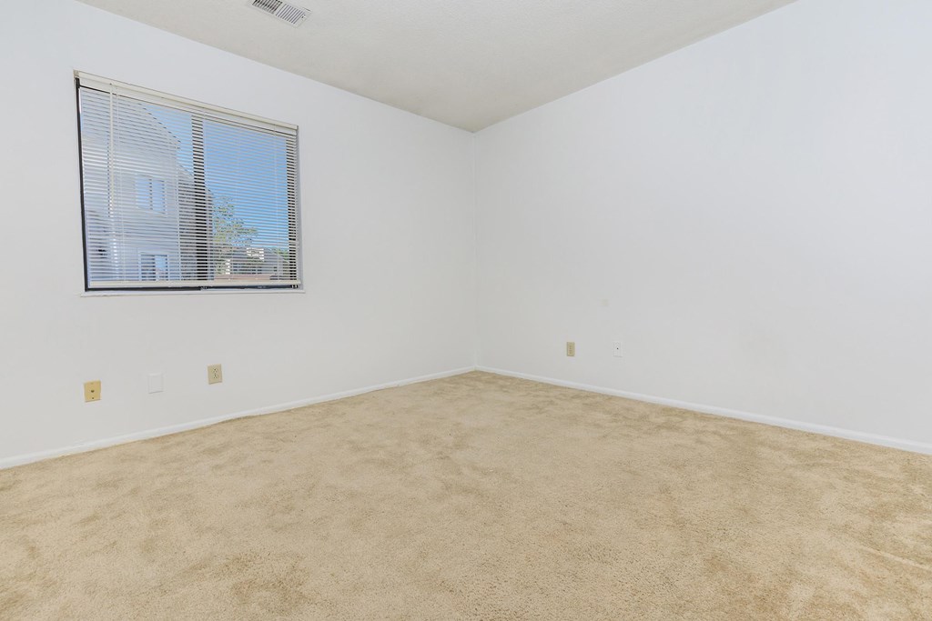 A room with a window and carpeted floor.