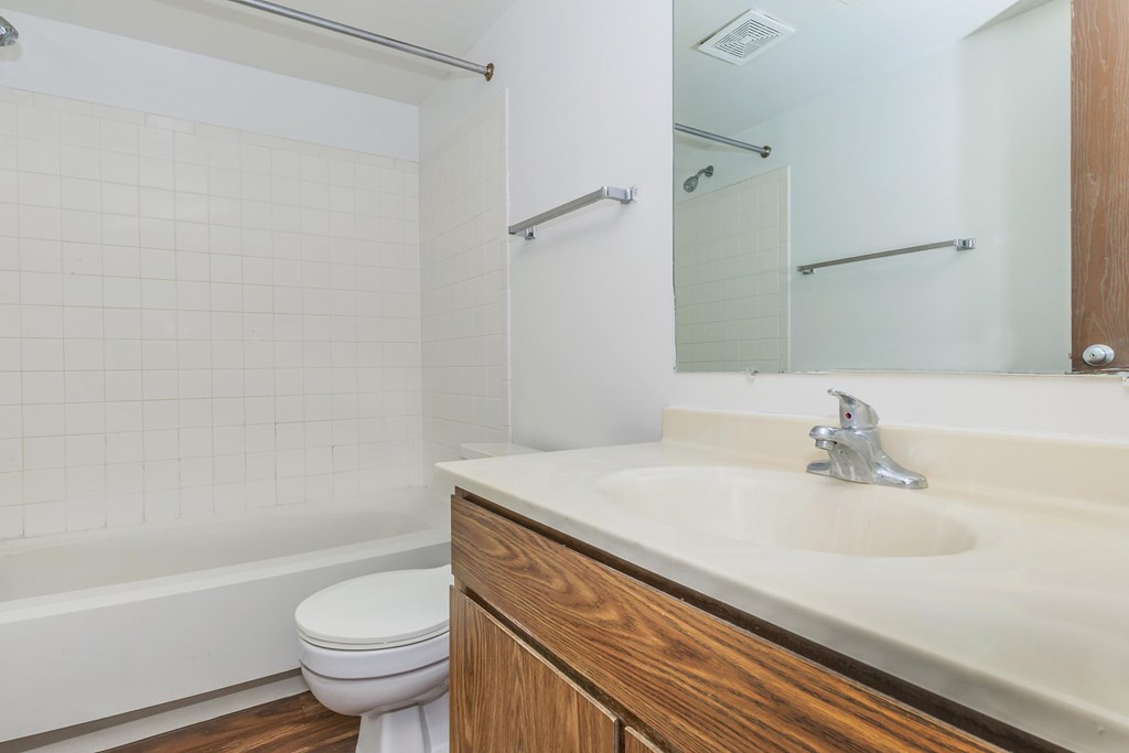 A white tiled bathroom with a toilet, sink, and bathtub.