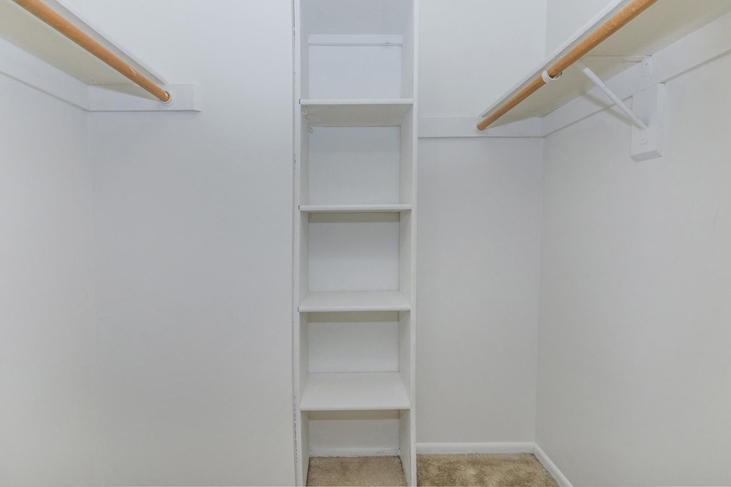 A white shelving unit with four shelves is mounted on a white wall.