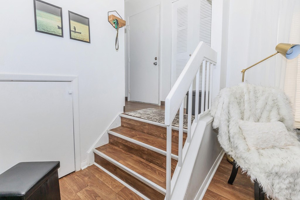 A white chair with a fluffy white blanket is in front of a staircase.