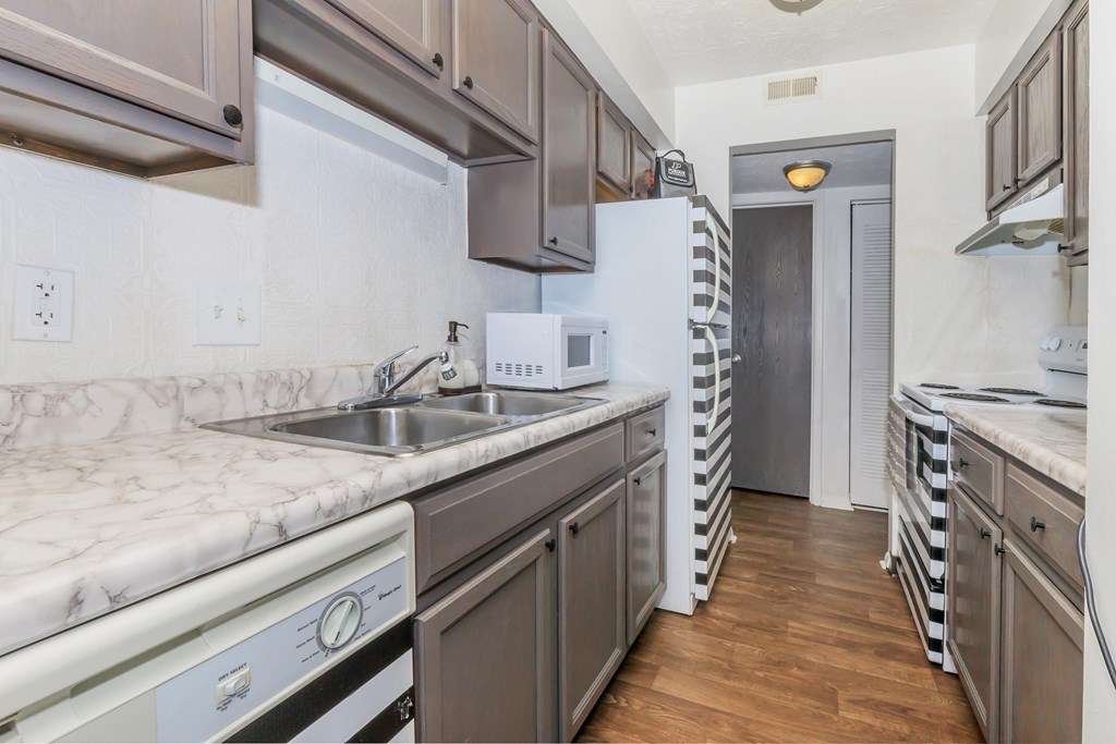 A kitchen with a white fridge and a white sink.