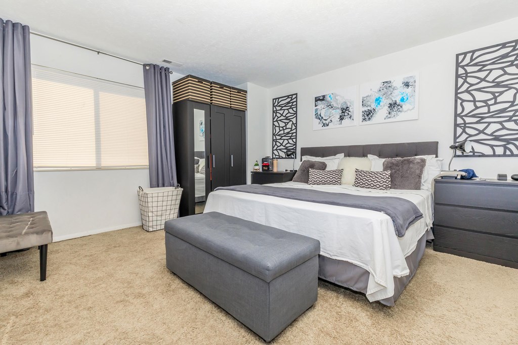 A bedroom with a large bed and a bench.