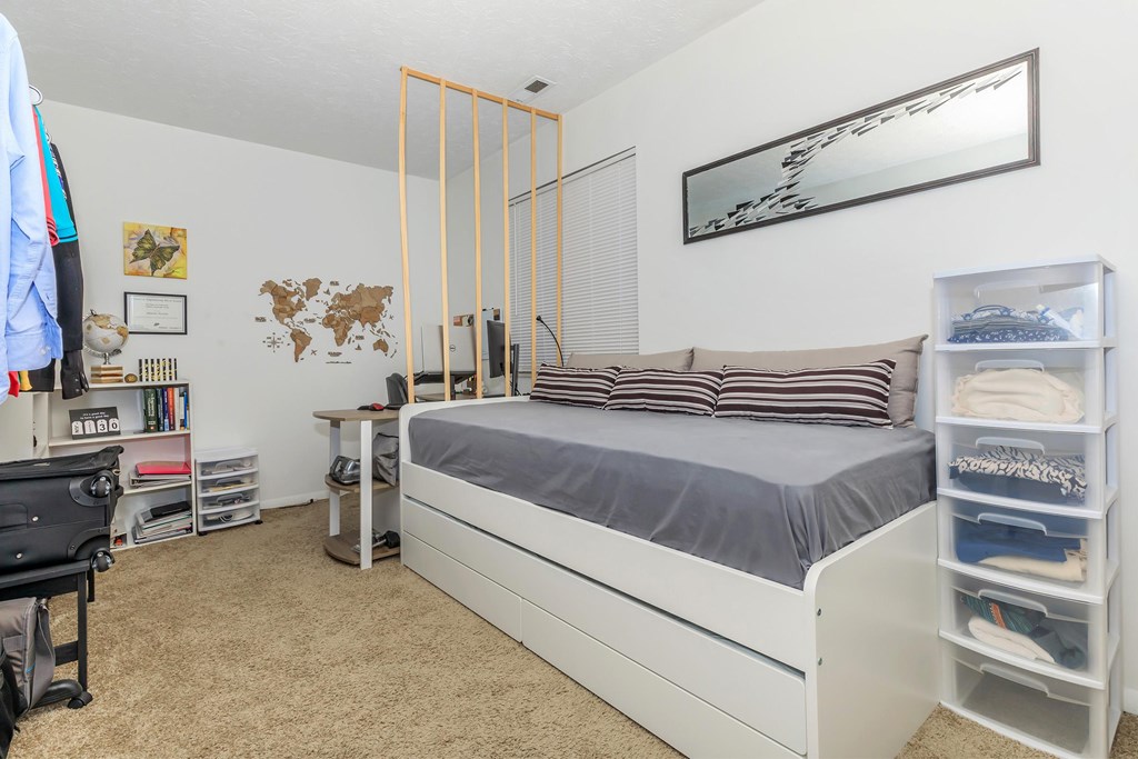 A bedroom with a bed, desk, and chair.