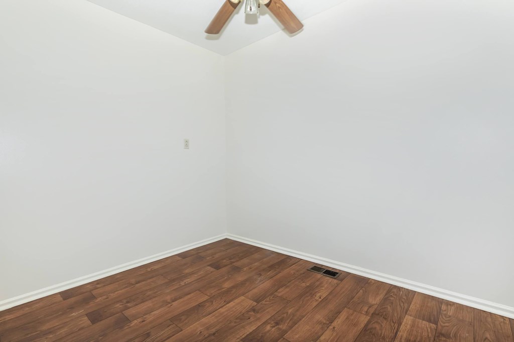 A room with a ceiling fan and wooden flooring.
