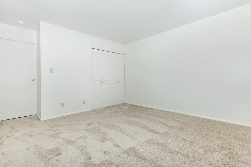 A room with a carpeted floor and two doors.