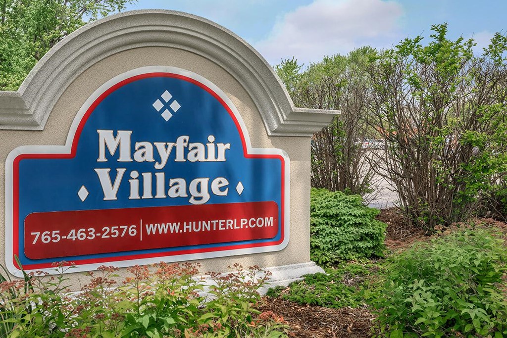 A sign for Mayfair Village with a phone number and website.
