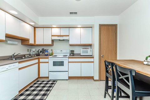 A kitchen with white cabinets and a black and white checkered rug.
