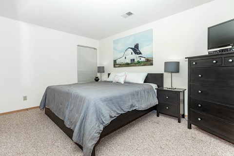 A bedroom with a bed, nightstand, and dresser.