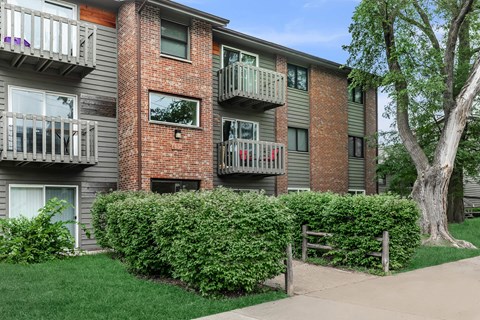 Apartment building with balconies and a tree in front.