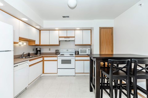 A kitchen with white appliances and wooden cabinets.