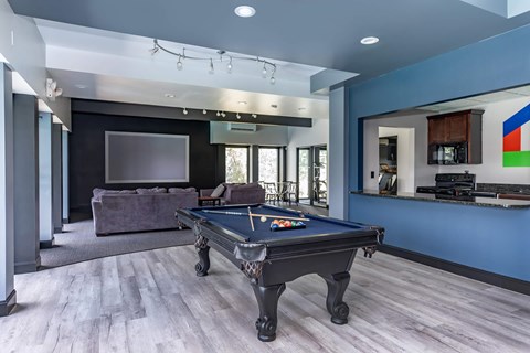 A pool table is in the middle of a room with a couch and a television.