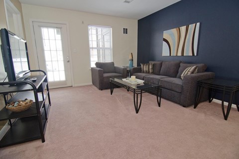 Living room with a grey couch and a painting on the wall.