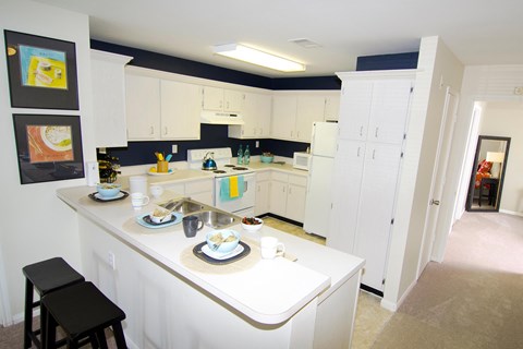 A kitchen with white cabinets and a black stool.