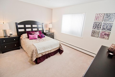 A bedroom with a large bed and a black dresser.