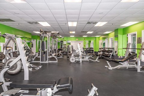 A gym with a variety of equipment including treadmills, weights, and exercise machines.