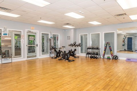 A gym with wooden floors and various exercise equipment.