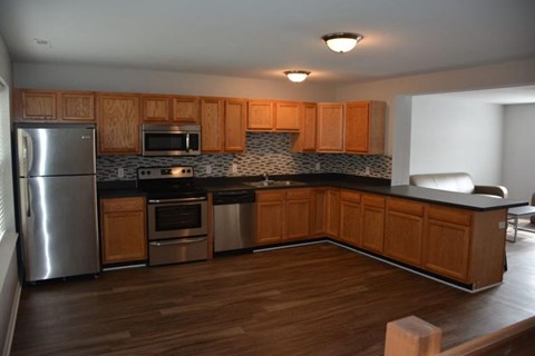 A kitchen with wooden cabinets and a stainless steel refrigerator.