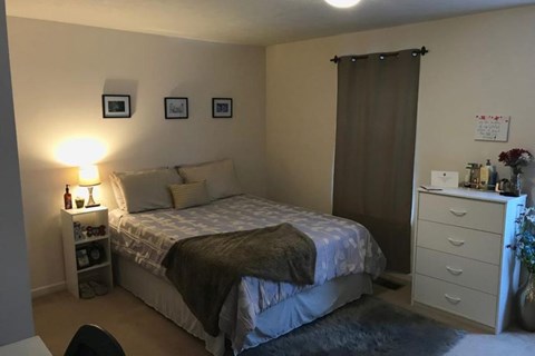 A bedroom with a bed, nightstand, and a chair.