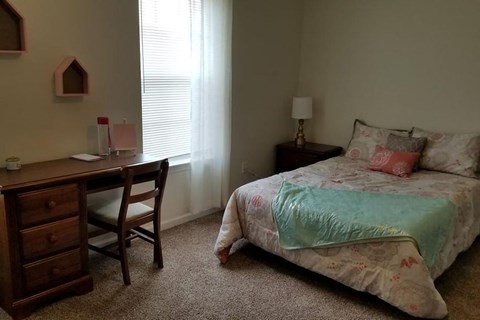 A bedroom with a bed, desk, and chair.