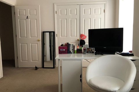 A white chair is in front of a white cabinet with a black television on top of it.
