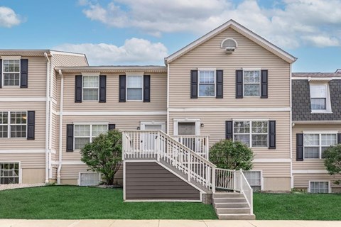 A two-story house with a staircase leading to the front door.