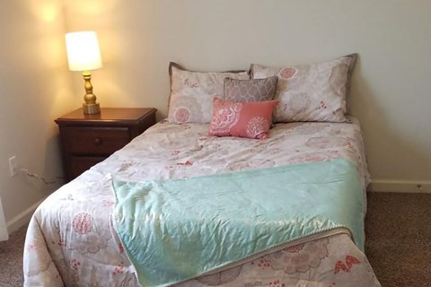 A bed with a white and pink comforter and a blue blanket is in the image.