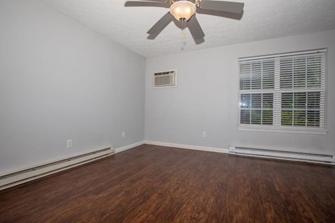 A room with a ceiling fan and wooden flooring.