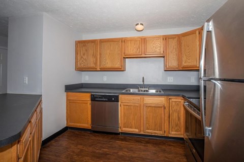 A kitchen with wooden cabinets and a stainless steel refrigerator.