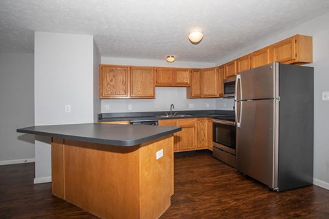 A kitchen with wooden cabinets and a stainless steel refrigerator.