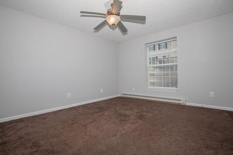 A room with a ceiling fan and carpeted floor.